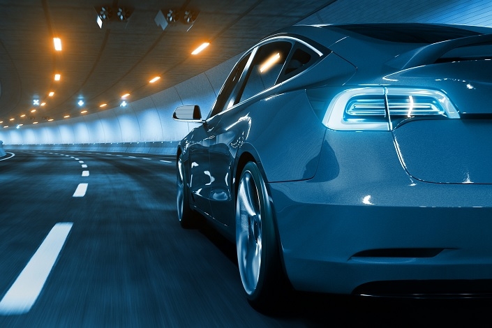 Modern Electric car rides through tunnel with warm yellow light 705x470